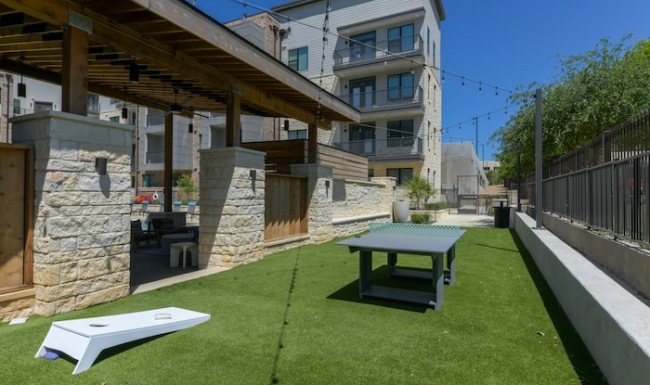 grass area with ping pong table and cornhole board